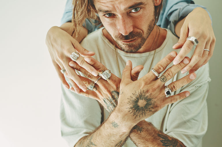 lifestyle photo image of man, holding woman's fingers, both wearing sterling silver Saint Vagabond rings