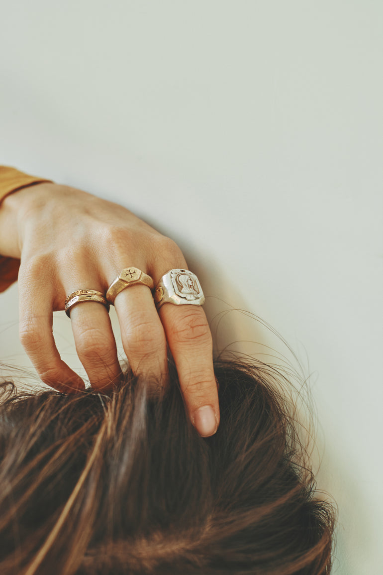 image of hand in hair, wearing multiple Saint Vagabond rings, Mother Mary ring and Sacred Love ring
