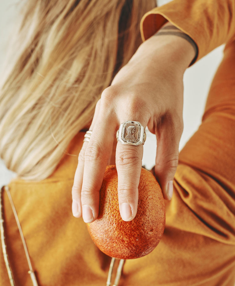 image of woman's hand holding an orange, wearing Mother Mary sterling silver ring 